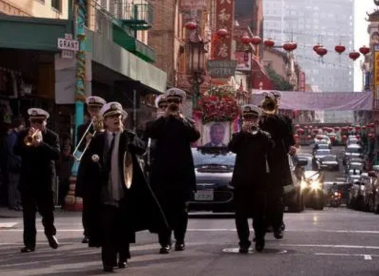 The Green Street Memorial Band (formerly Green Street Mortuary Band) leading a procession through Grant Avenue in Chinatown, with the street lined with traditional Chinese and Vietnamese decorations for a memorial service